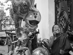 Devant la porte du monastère, un marchand à vélo de baudruches, a fait une halte pour le plus grand bonheur des petits moines...